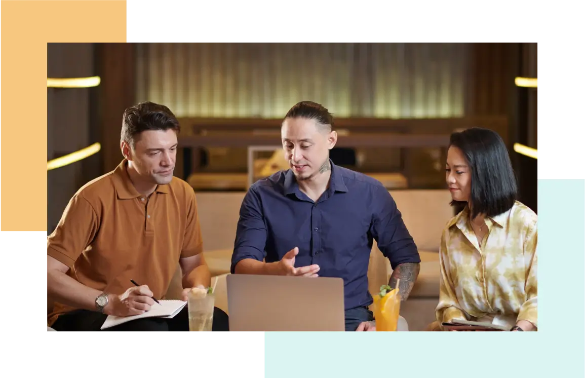Three people working together around a laptop